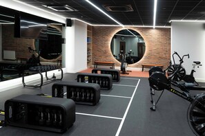 Una palestra con attrezzature per esercizi, uno specchio e un muro in mattoni.