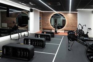Gimnasio con equipo de ejercicio, un espejo y una pared de ladrillo.