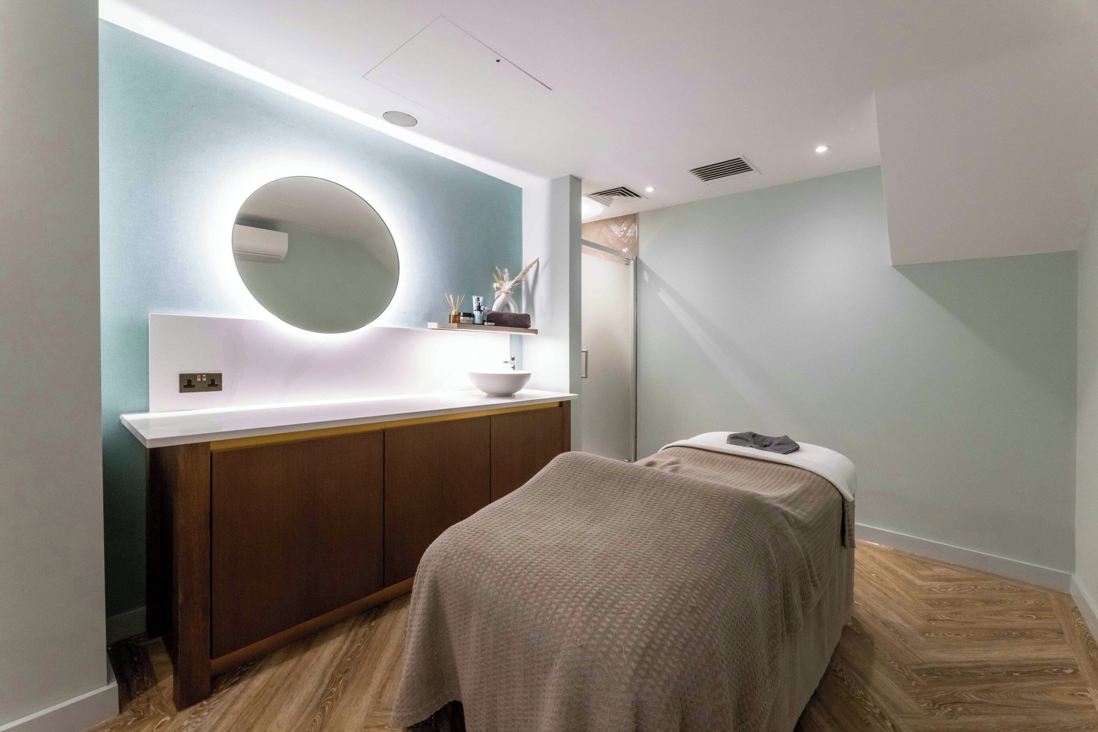 Une salle de bain moderne avec un miroir rond, un lavabo blanc et un meuble en bois.