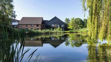 Een rustige woonwijk met een huis aan een kalm meer, omgeven door weelderige begroeiing en bomen.