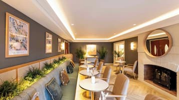 A modern interior with a long sofa, round tables, and a fireplace.