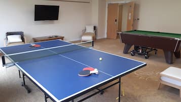 Enjoy games and entertainment in this room featuring a ping pong table, pool table, and TV.