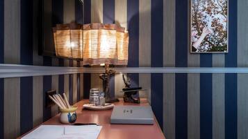 Ein Schreibtisch mit Lampe, Notizbuch, Stift, Glas und einer dekorativen Skulptur.