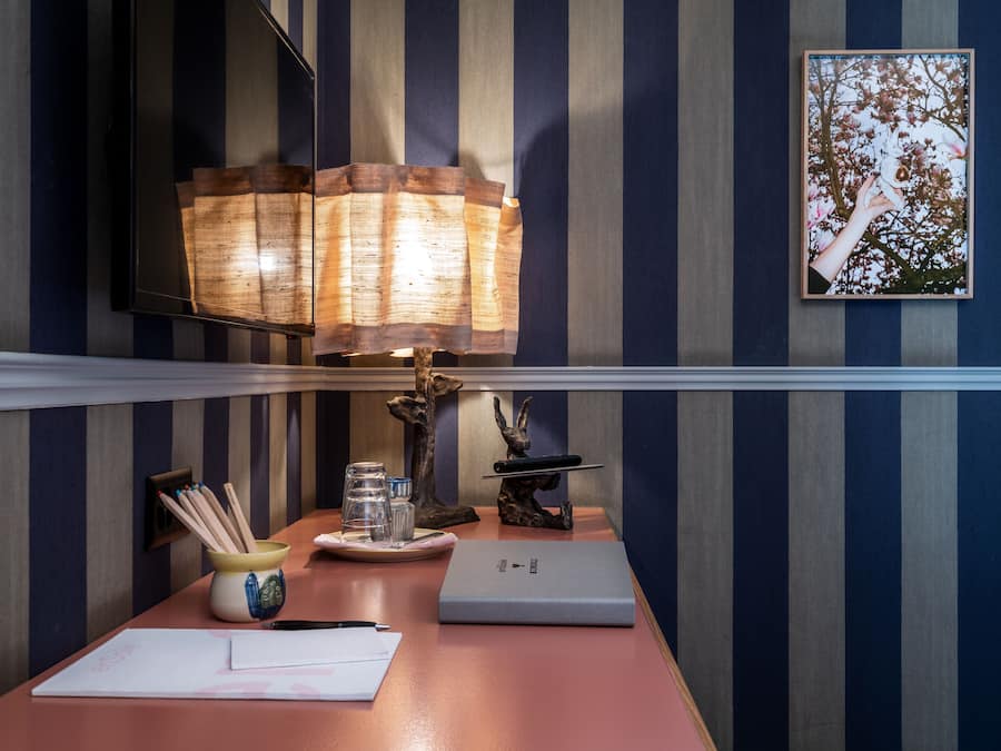 Ein Schreibtisch mit Lampe, Notizbuch, Stift, Glas und einer dekorativen Skulptur.