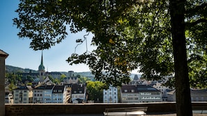Un banc dans un parc, avec vue sur la ville et le clocher d’une église.