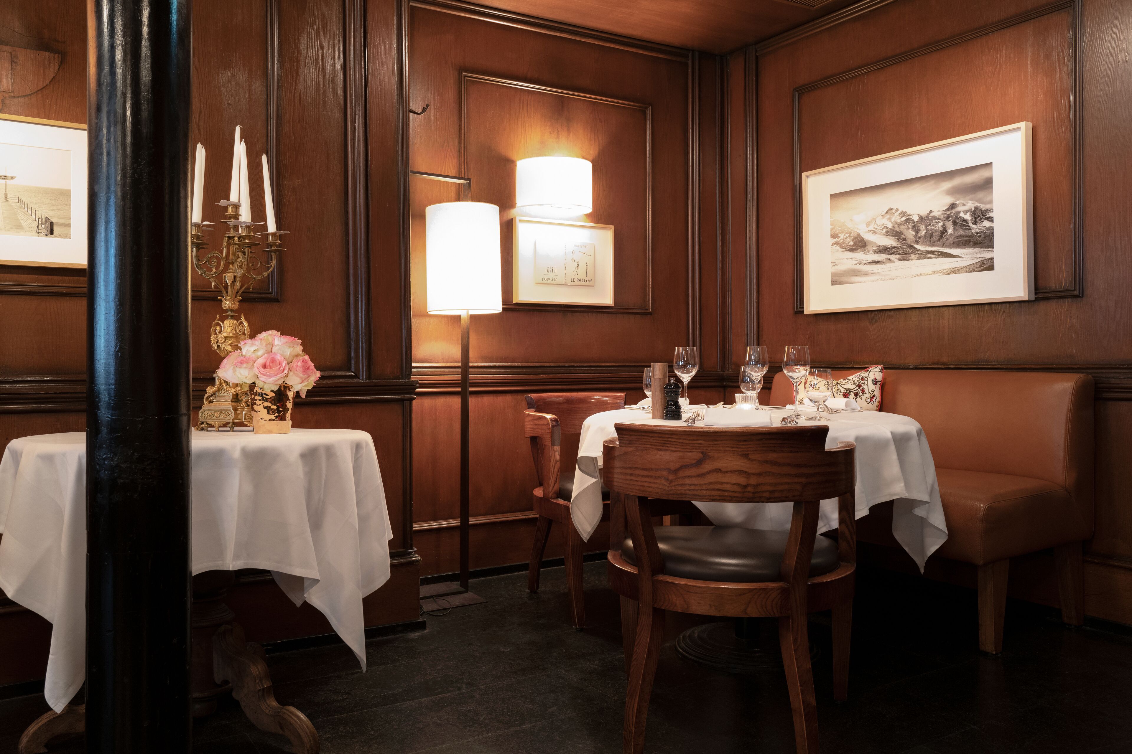 Un comedor con paneles de madera, una mesa cubierta con mantel blanco, un jarrón de flores y un cuadro en la pared.