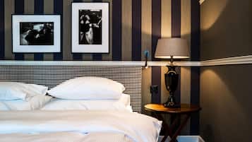 A hotel room with a bed, a nightstand with a lamp, and two framed pictures on the wall.