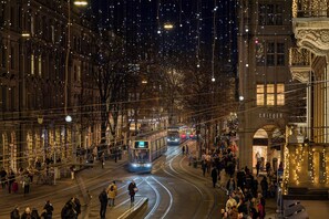 A tram moving through a city street at night, surrounded by buildings with illuminated decorations. - Hotel Kindli (Zürich)