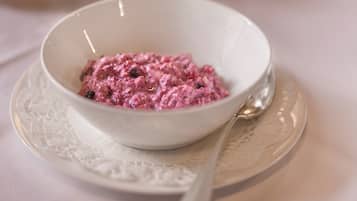 A white bowl of pink food on a white plate with a spoon.
