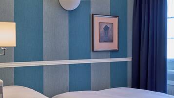 Una habitación de hotel con una cama, una lámpara de pared y un cuadro enmarcado.