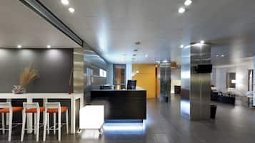 A modern reception area with a counter, bar stools, and a seating area with chairs and a table.