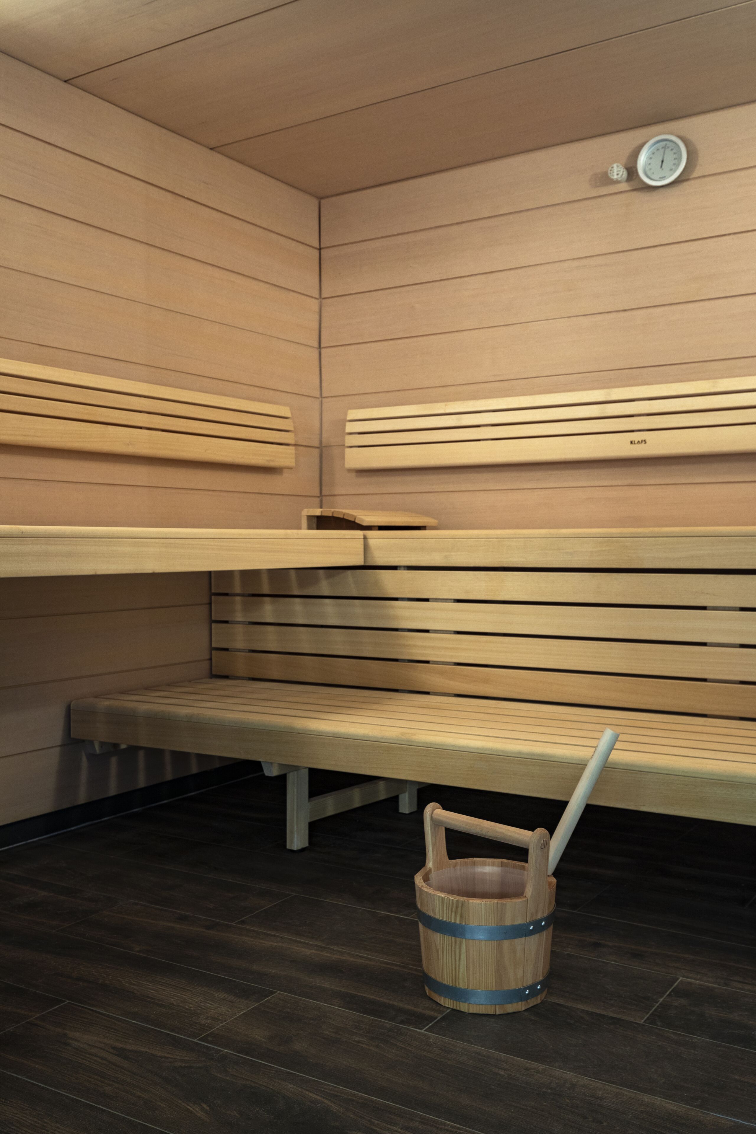 A sauna with wooden benches and a wooden bucket with a handle.