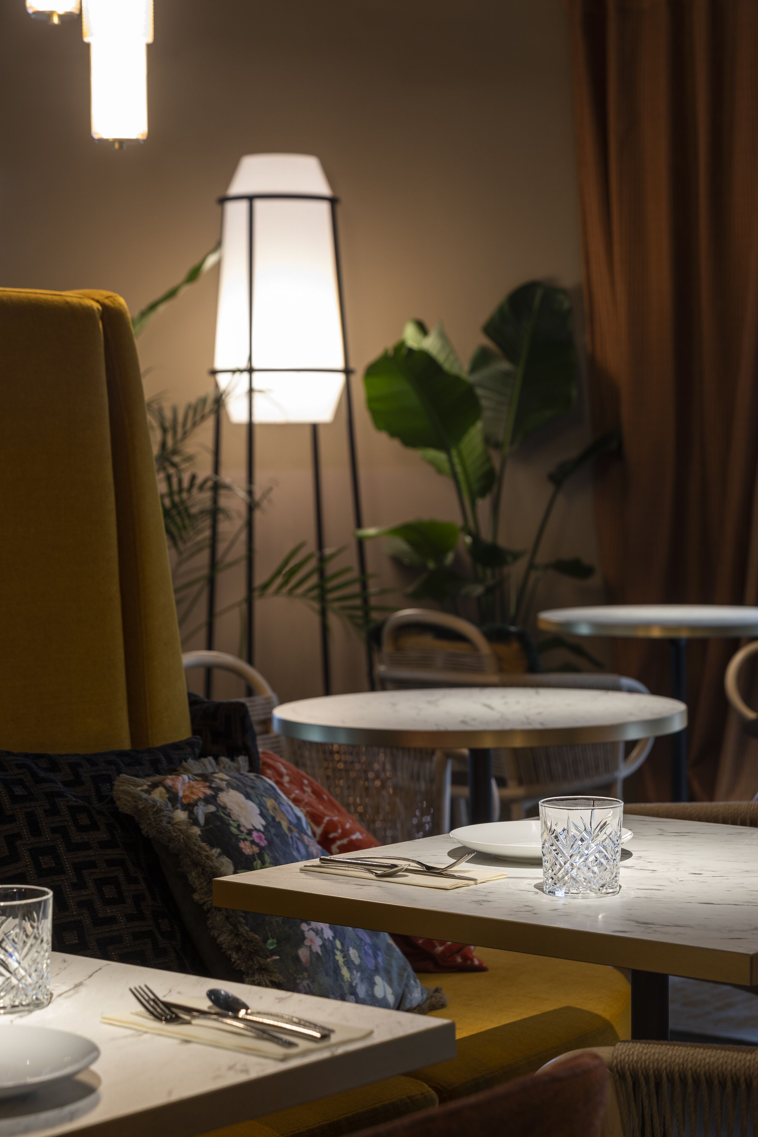 Un espace repas avec des tables, des chaises et une lampe.