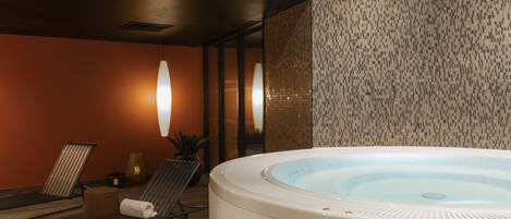 A spa area with a hot tub, lounge chairs, and a textured wall.