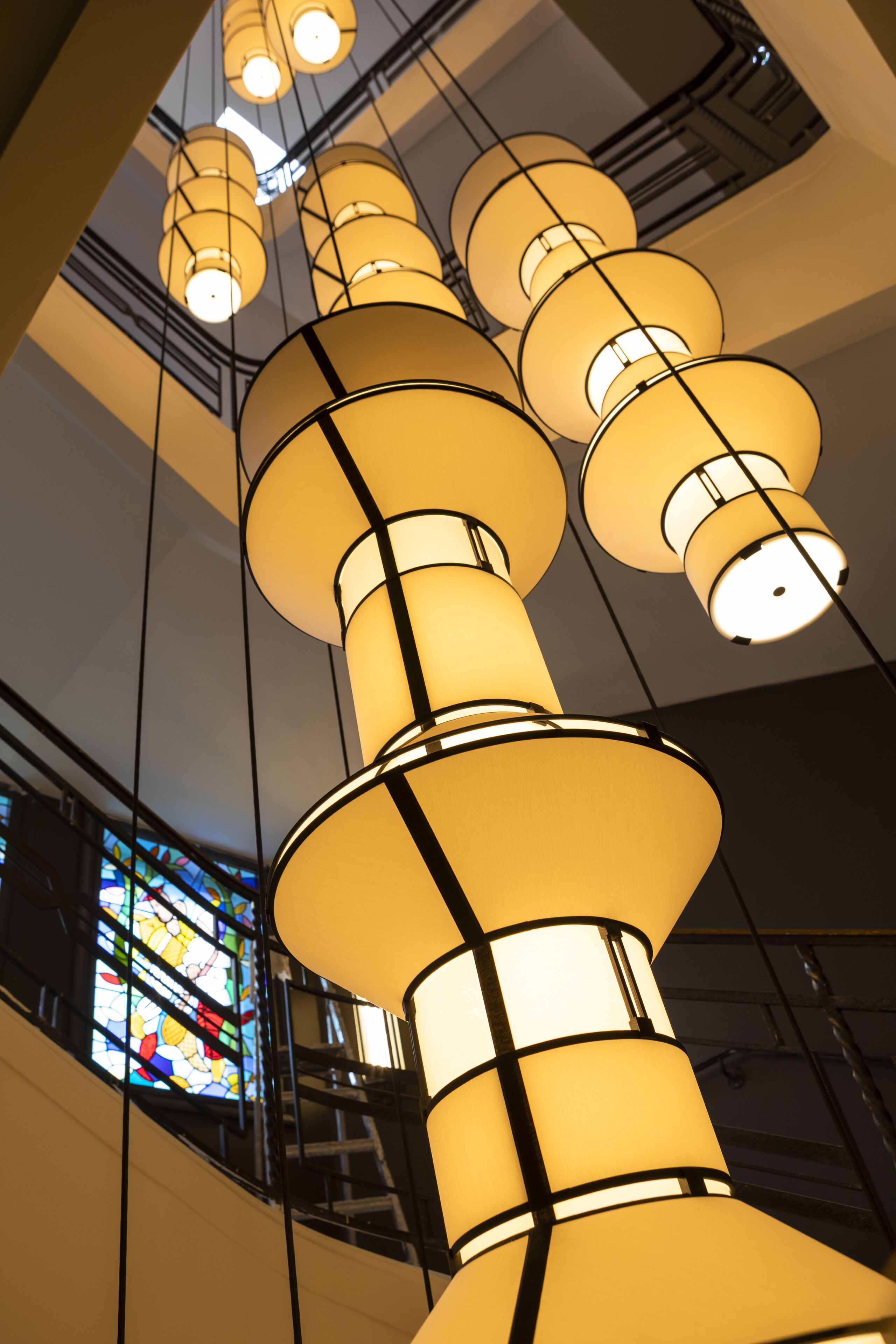 A series of cylindrical light fixtures suspended from the ceiling in a building.