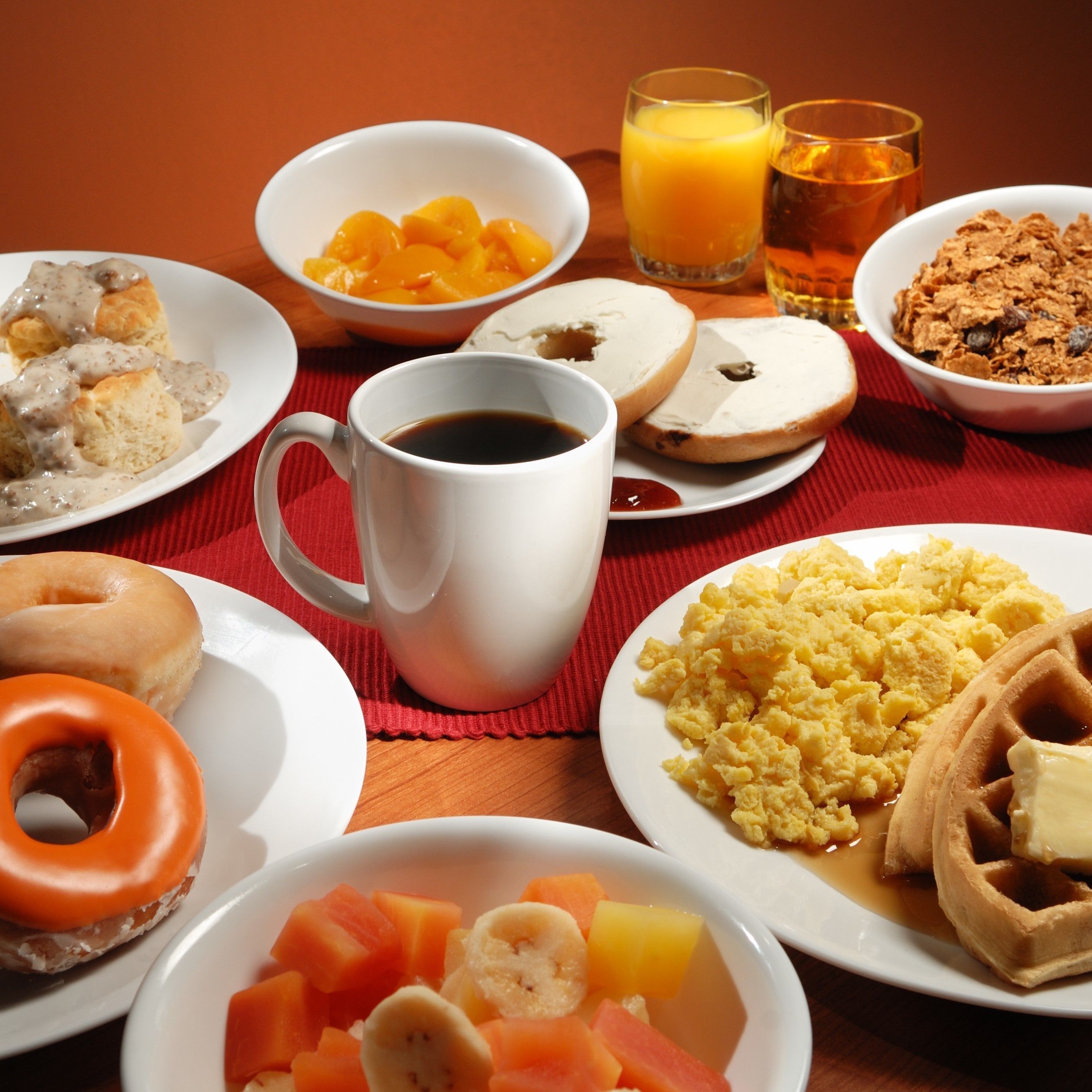 Une table de petit-déjeuner avec divers plats, notamment des gaufres, des œufs brouillés et un beignet.