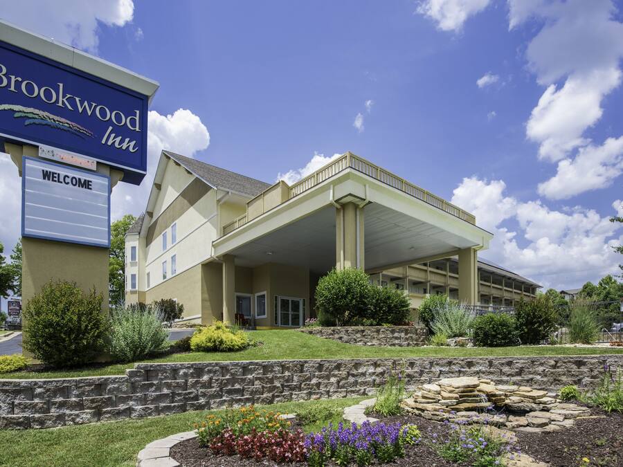 Un hotel con un cartel llamativo que dice "Brookwood Inn" y una señal de bienvenida debajo.