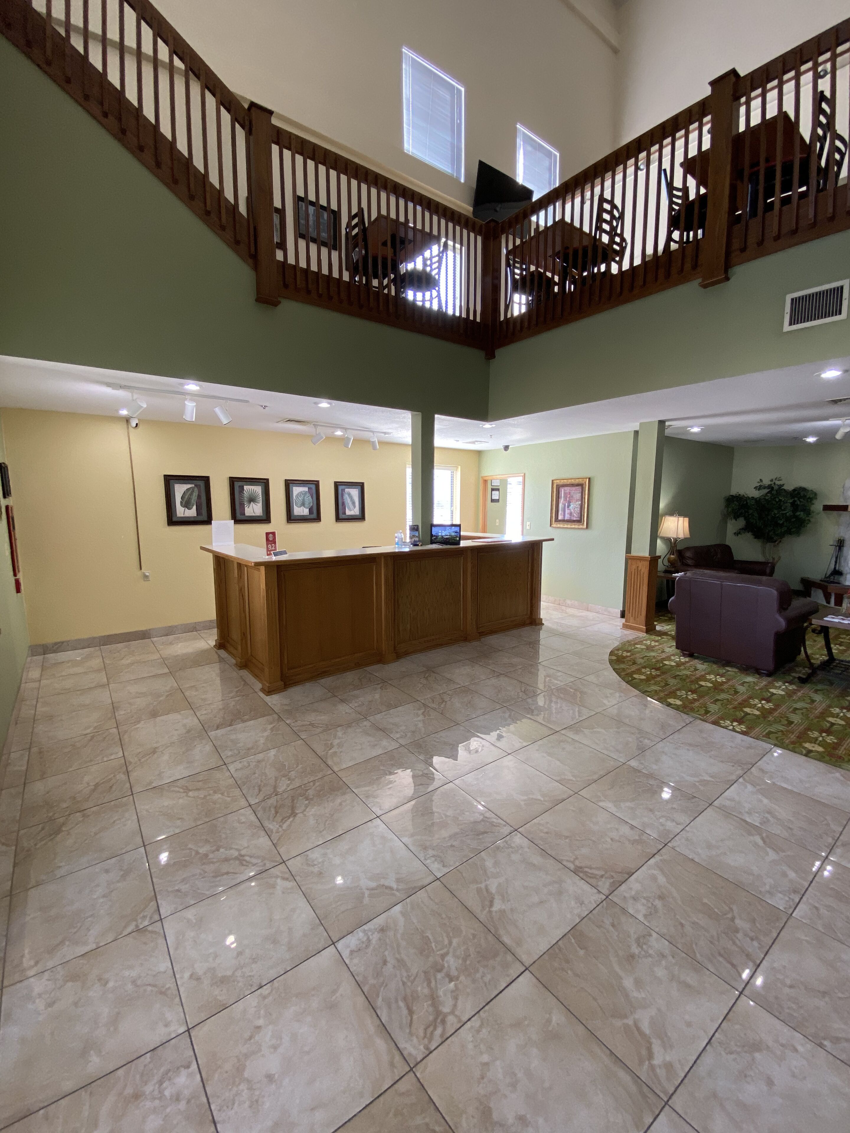 A spacious lobby with a high ceiling, a wooden staircase, and a reception desk.