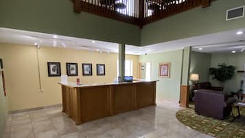 A spacious lobby with a high ceiling, a wooden staircase, and a reception desk.