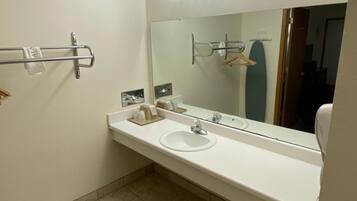 A bathroom with a white sink, mirror, towel rack, and a trash bin.