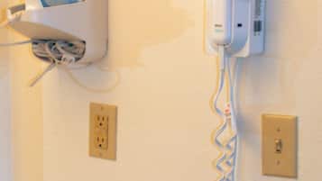 A wall-mounted device with a cord, possibly a security or communication device, and a power outlet below it.