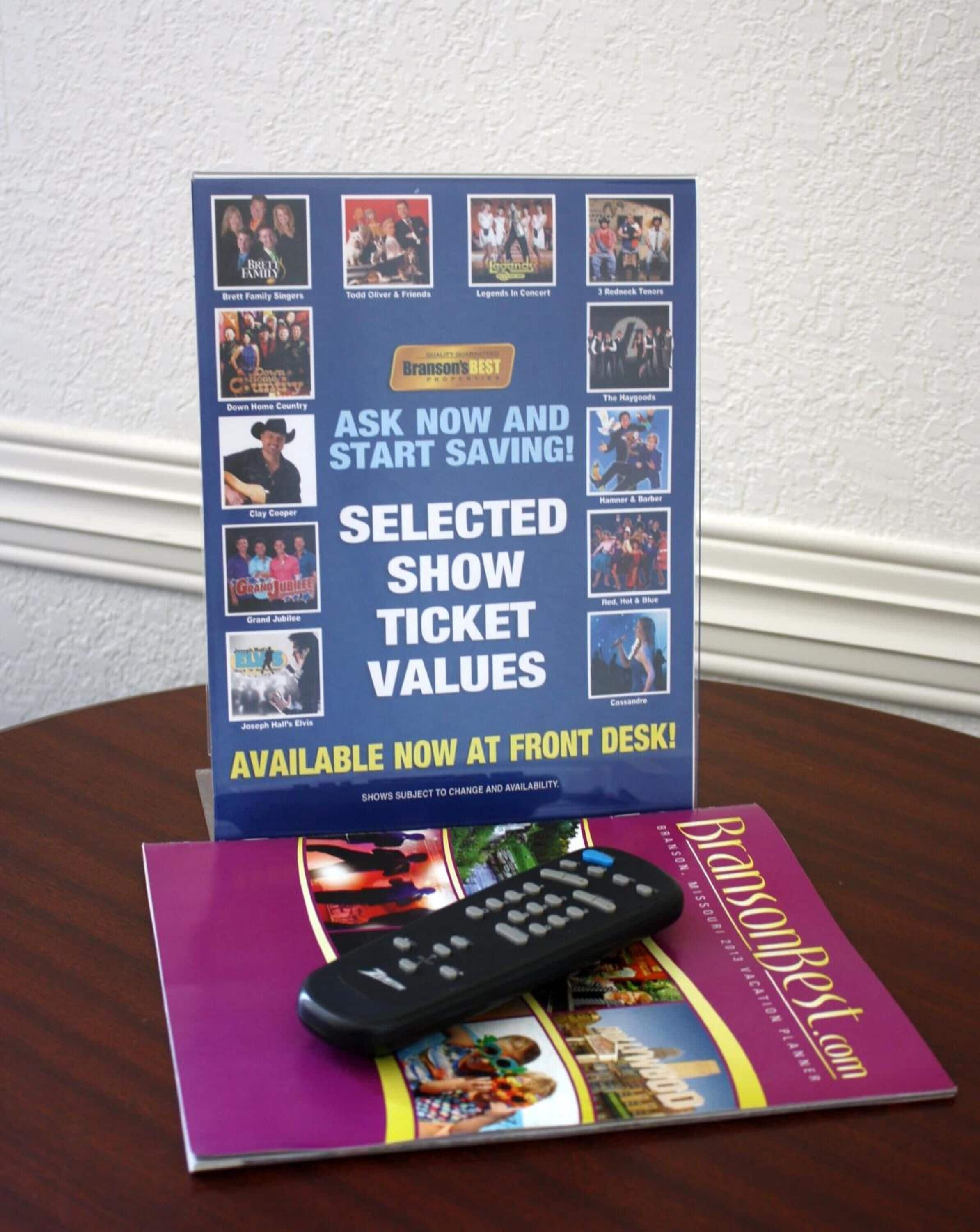 A display stand with show tickets and a remote control on a table.
