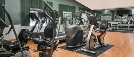 A gym with various cardio and strength training equipment, including treadmills, elliptical machines, and weight machines.