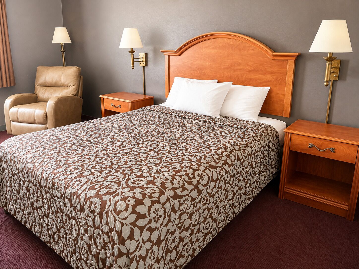 A hotel room with a large bed, two bedside tables, a chair, and two wall-mounted lamps.