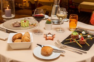 Uma mesa de jantar posta com diversos pratos, copos de vinho e uma vela.