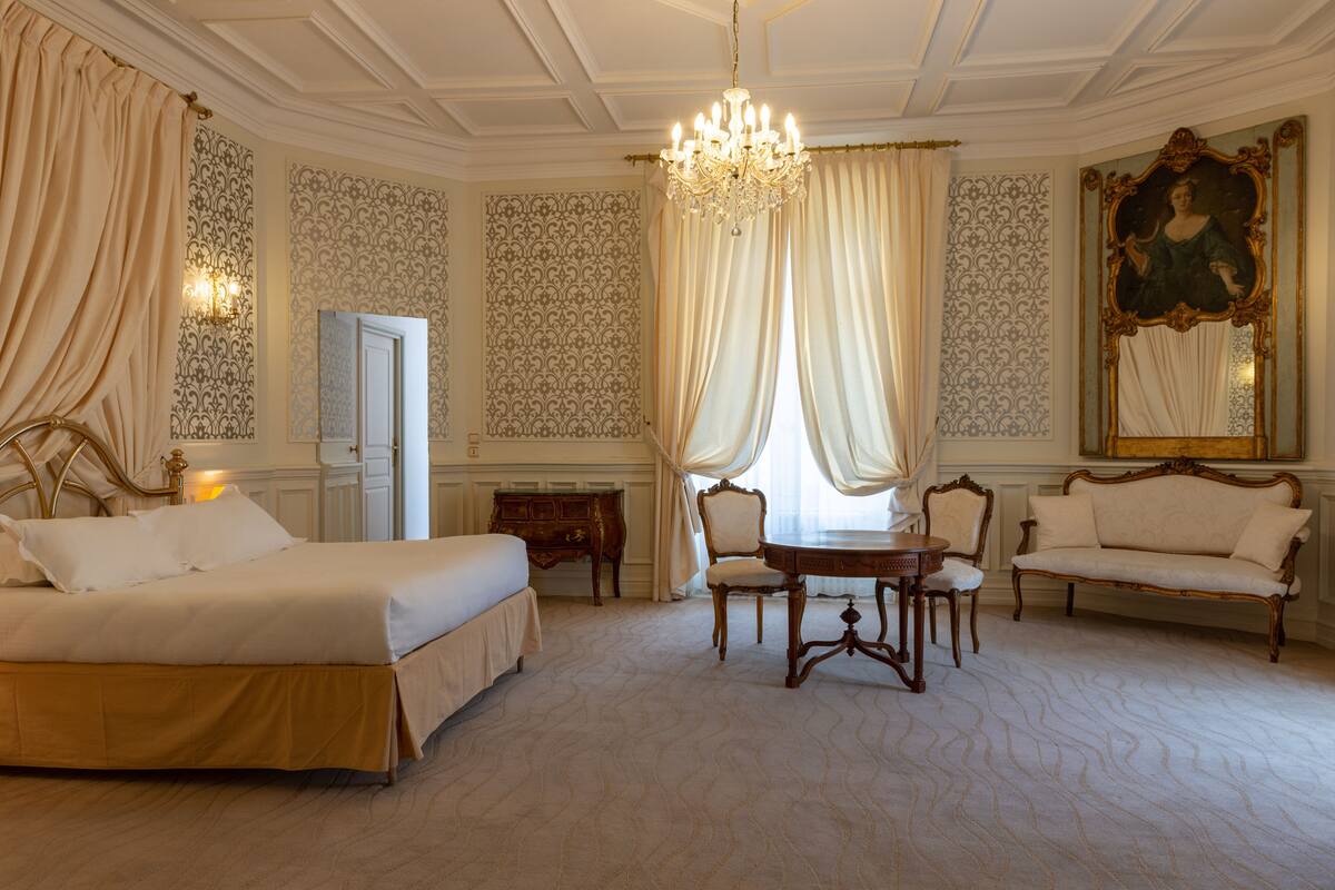 A spacious room with a large bed, a dining table, and a sofa.