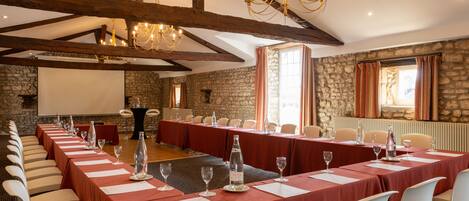 A conference room with a long table set for a meeting, stone walls, and a chandelier.