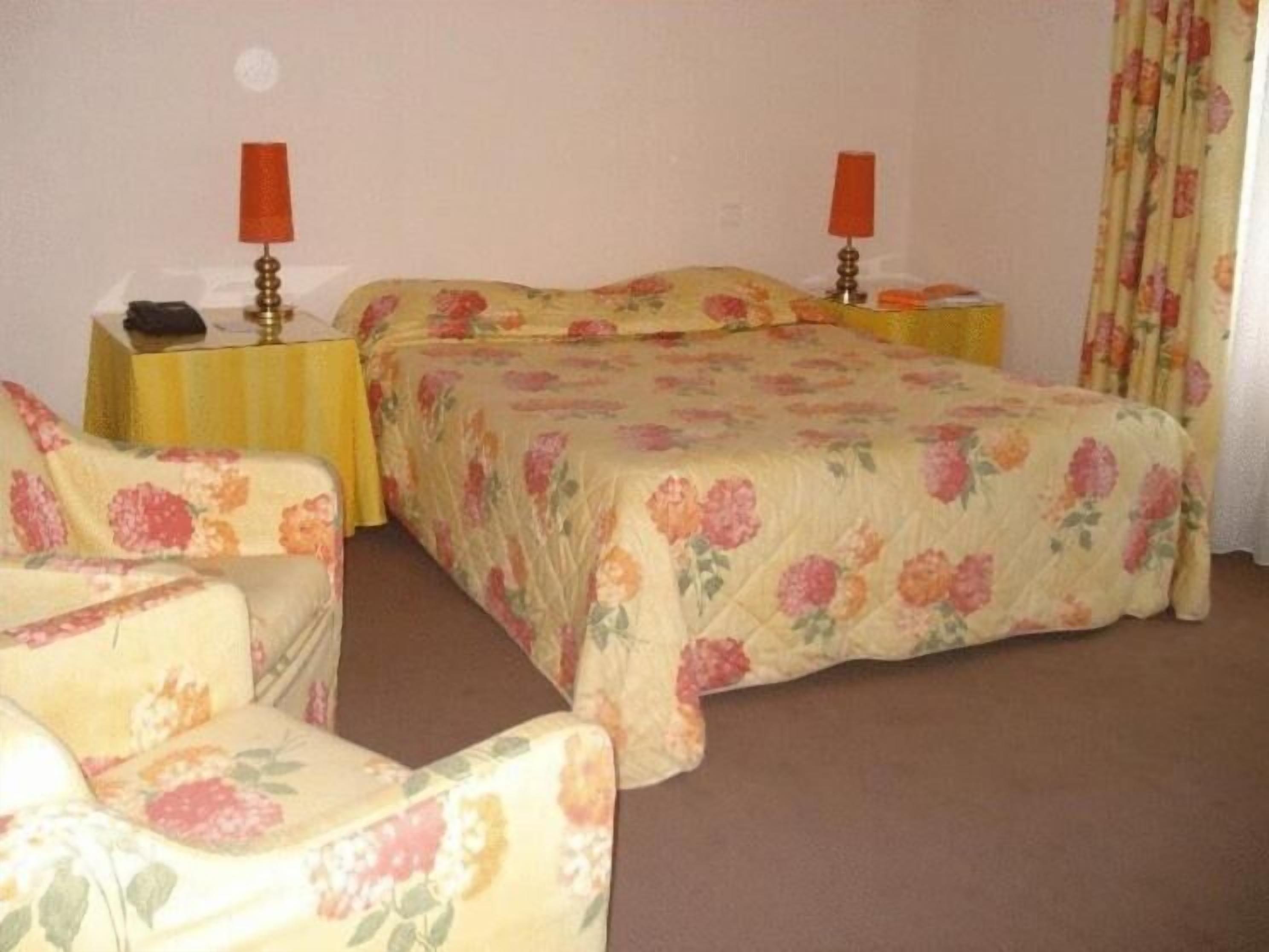 Un dormitorio con una cama, dos mesitas de noche y una silla.