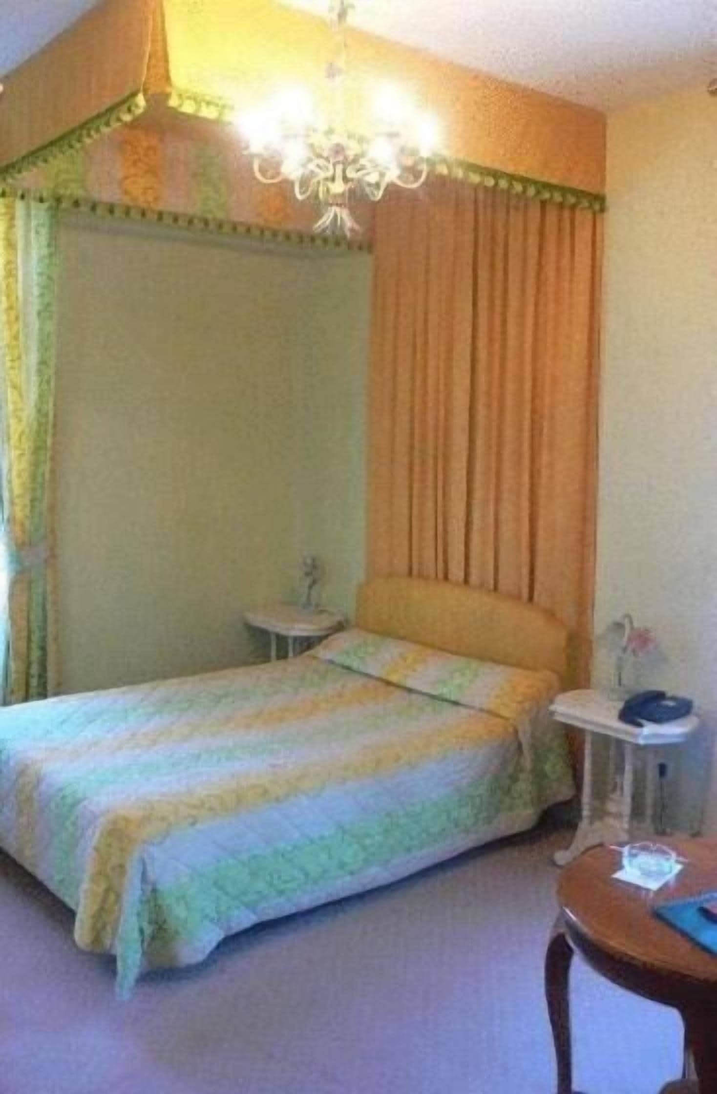 A bedroom with a canopy bed, a bedside table, and a nightstand.