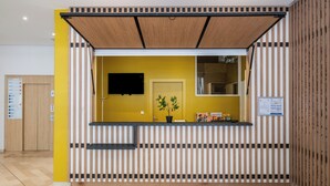 Ein Empfangsbereich mit Holzlamellen-Design, einer Zimmerpflanze und einem Wandfernseher.