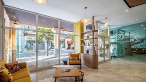 Eine moderne Hotelhalle mit großen Fenstern, einer Sitzecke mit Tisch und einer Rezeption.