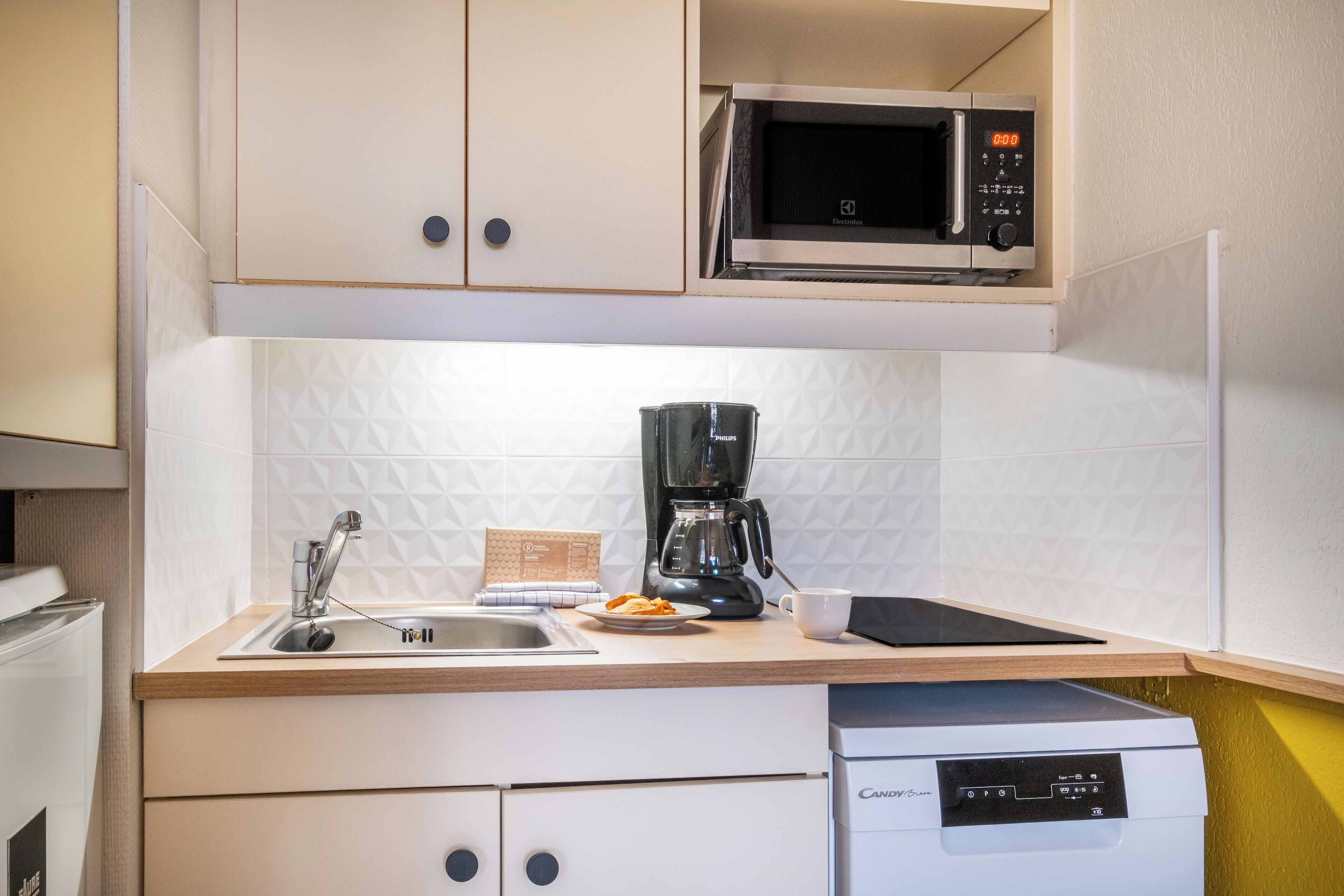 A kitchen with a microwave, coffee maker, sink, and a dishwasher.