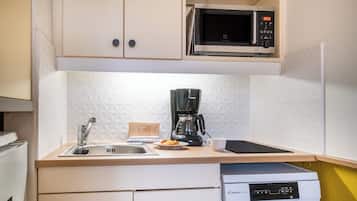 A kitchen with a microwave, coffee maker, sink, and a dishwasher.