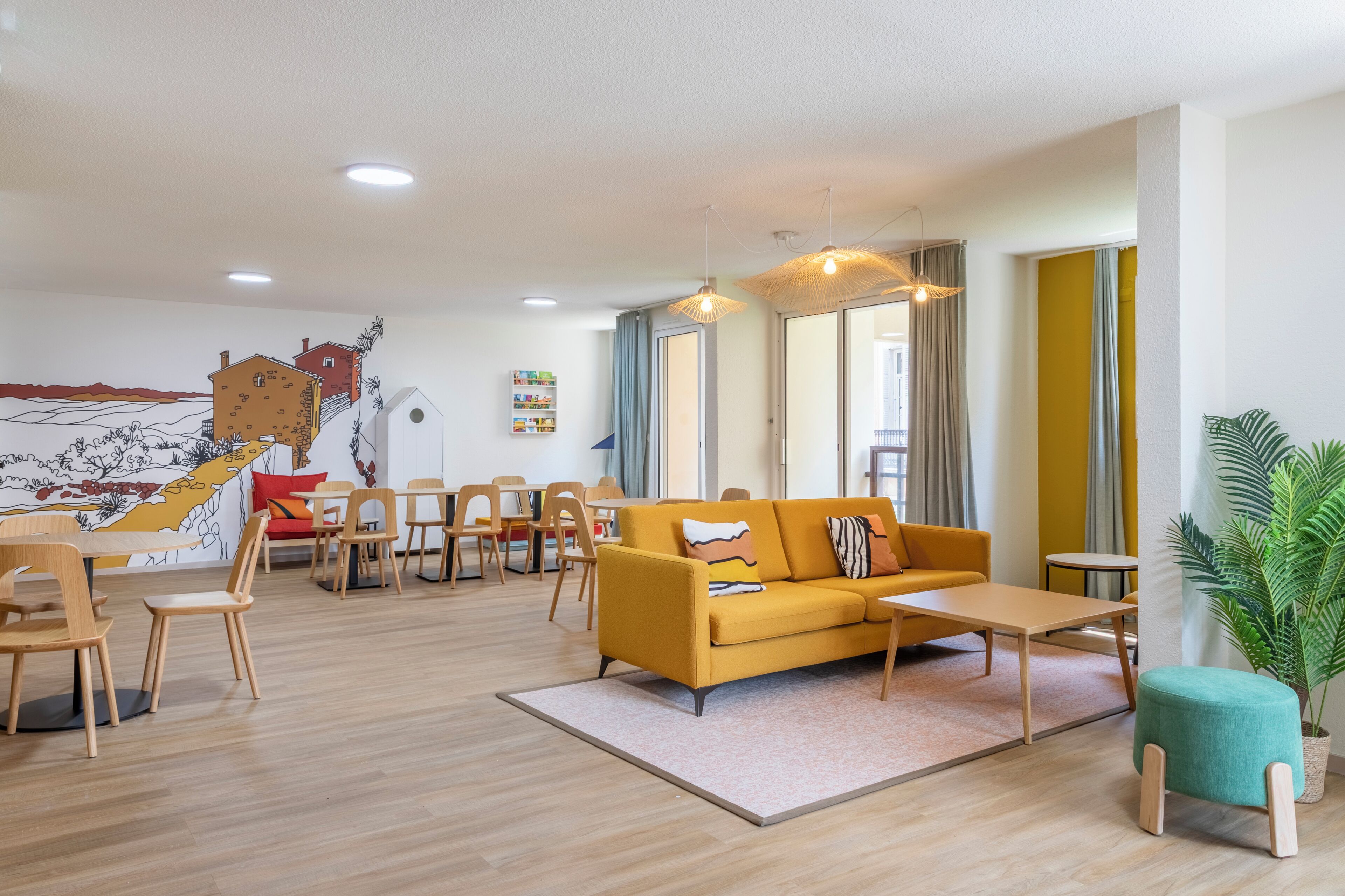 Ein modernes Wohnzimmer mit einem gelben Sofa, Holzstühlen, einem kleinen Tisch und einem großen Fenster mit Vorhängen.