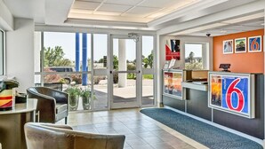 Een hotel lobby met een receptiebalie, een zithoek en grote ramen met uitzicht op het omliggende landschap.