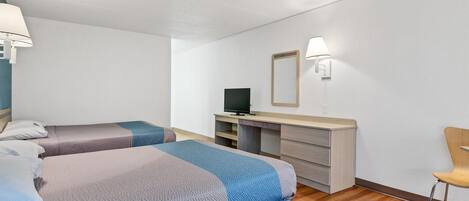 A hotel room with two beds, a desk, a chair, and a TV.