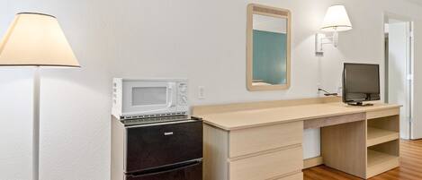 Una kitchenette compacta equipada con microondas, estufa, refrigerador y un televisor pequeño.