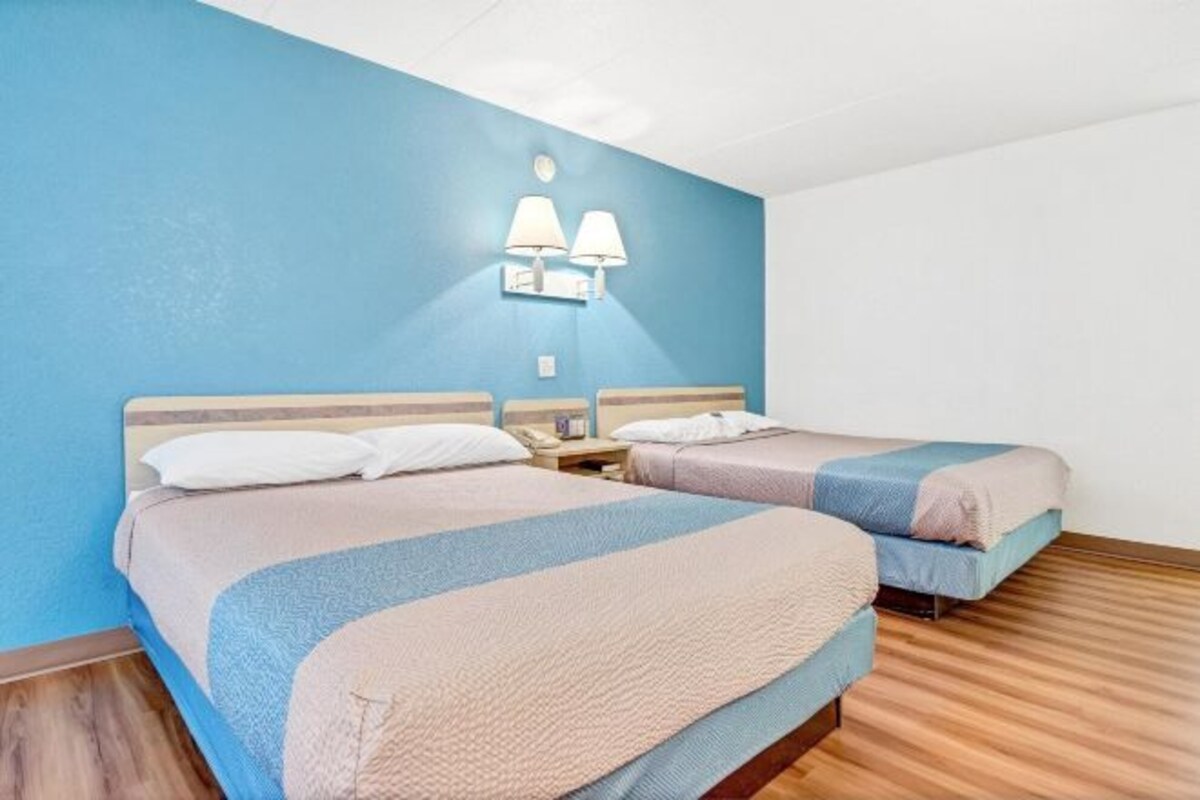 A hotel room with two beds, a blue wall, and a wooden floor.