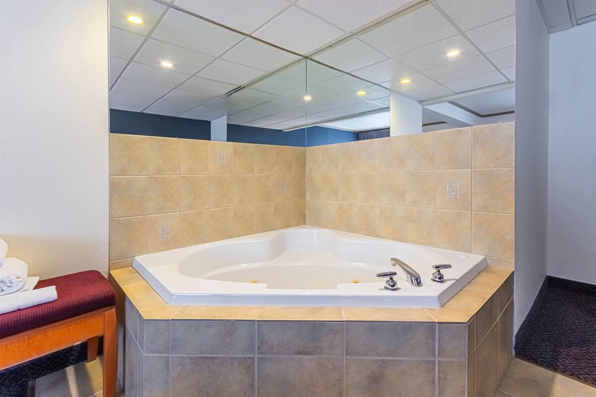 A modern bathroom with a freestanding bathtub, a bench, and tiled walls.