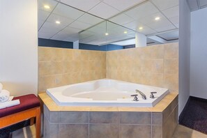 Une salle de bain moderne avec une baignoire sur pieds, un banc et des murs carrelés.