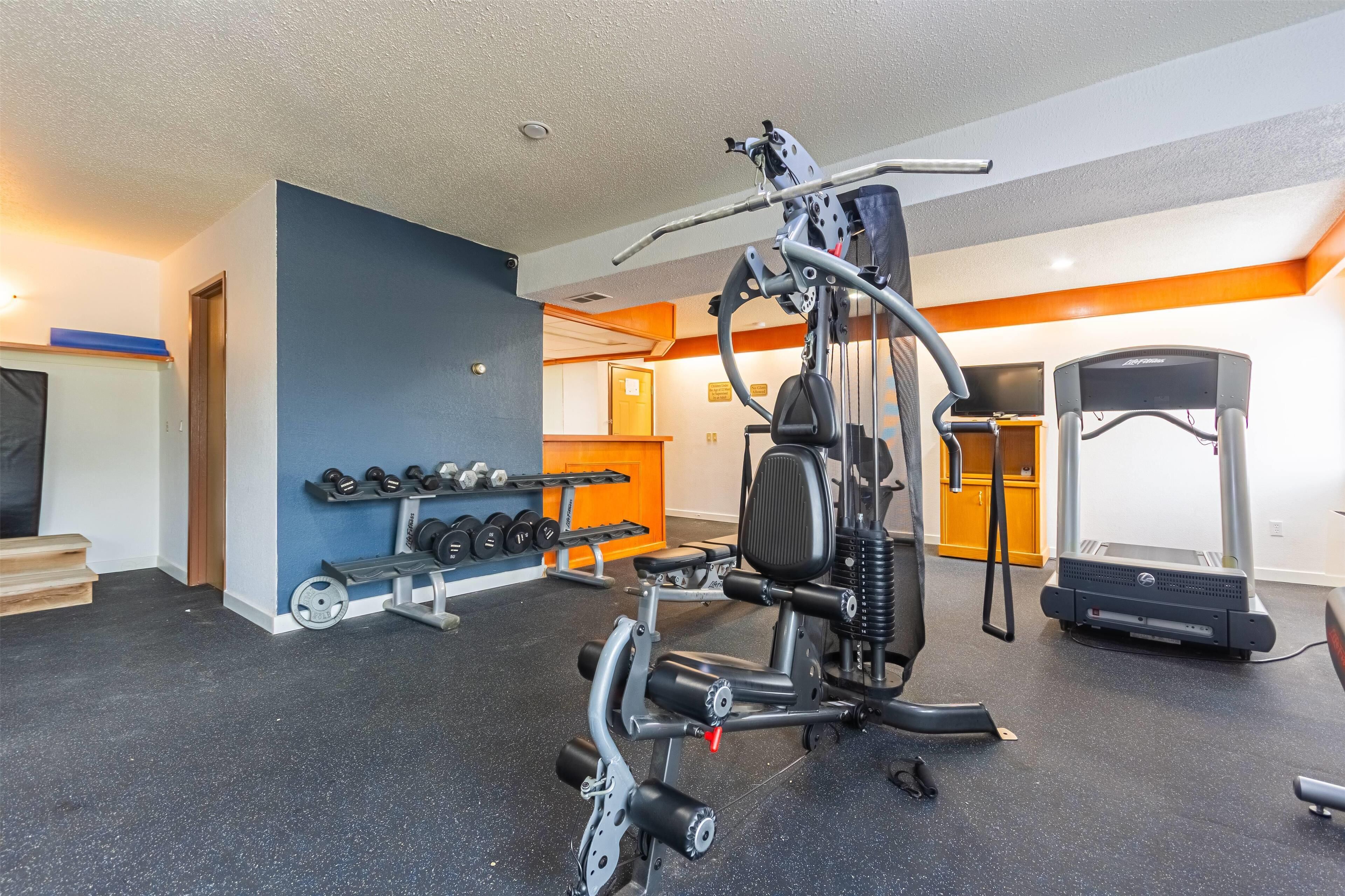 Ett gym med träningsredskap, hantlar och ett löpband.