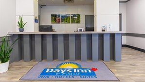 A reception desk with a 'Days Inn by Wyndham' sign, a plant, and a framed landscape picture on the wall.