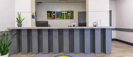 A reception desk with a 'Days Inn by Wyndham' sign, a plant, and a framed landscape picture on the wall.