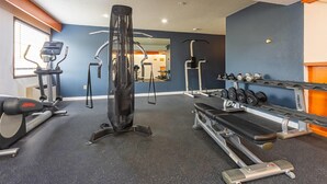 A gym with cardio machines, weightlifting equipment, and dumbbells.