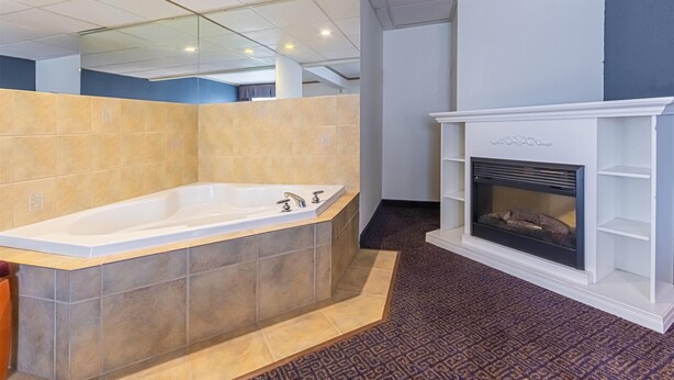 A modern bathroom with a large bathtub, a fireplace, and a tiled floor.