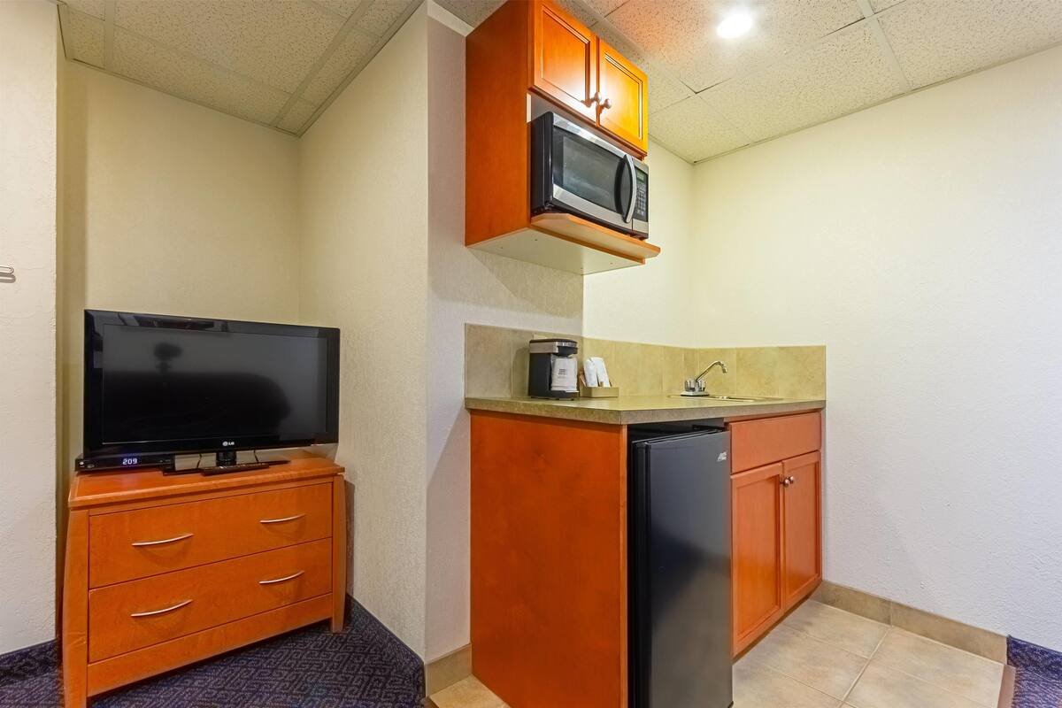 A compact kitchen with a microwave, a coffee maker, and a refrigerator.